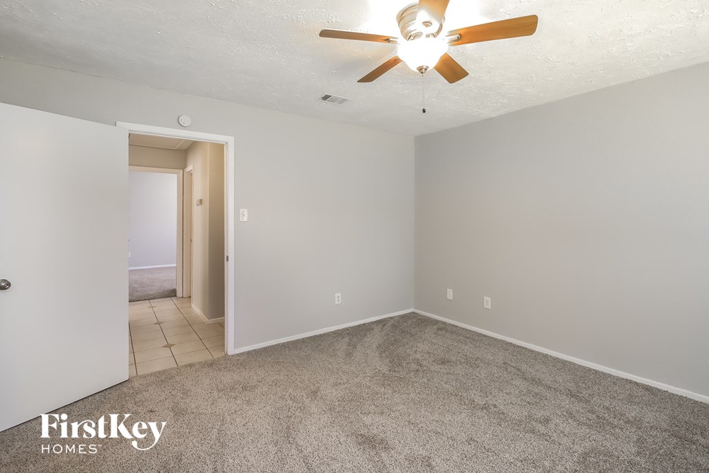 a empty living room with a ceiling fan and carpet