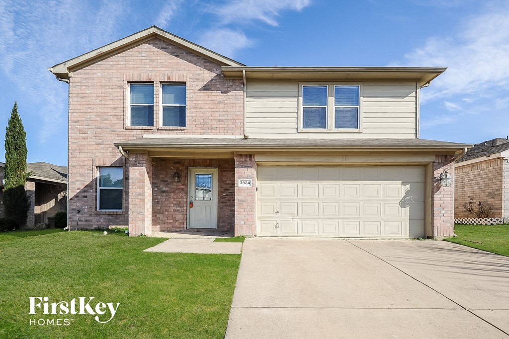 a tan brick house with a white garage door
