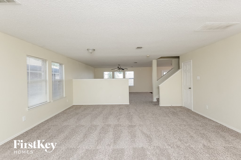 the living room and dining room of an apartment with carpeted flooring