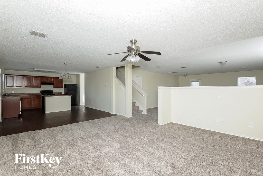 an empty living room and kitchen with a ceiling fan