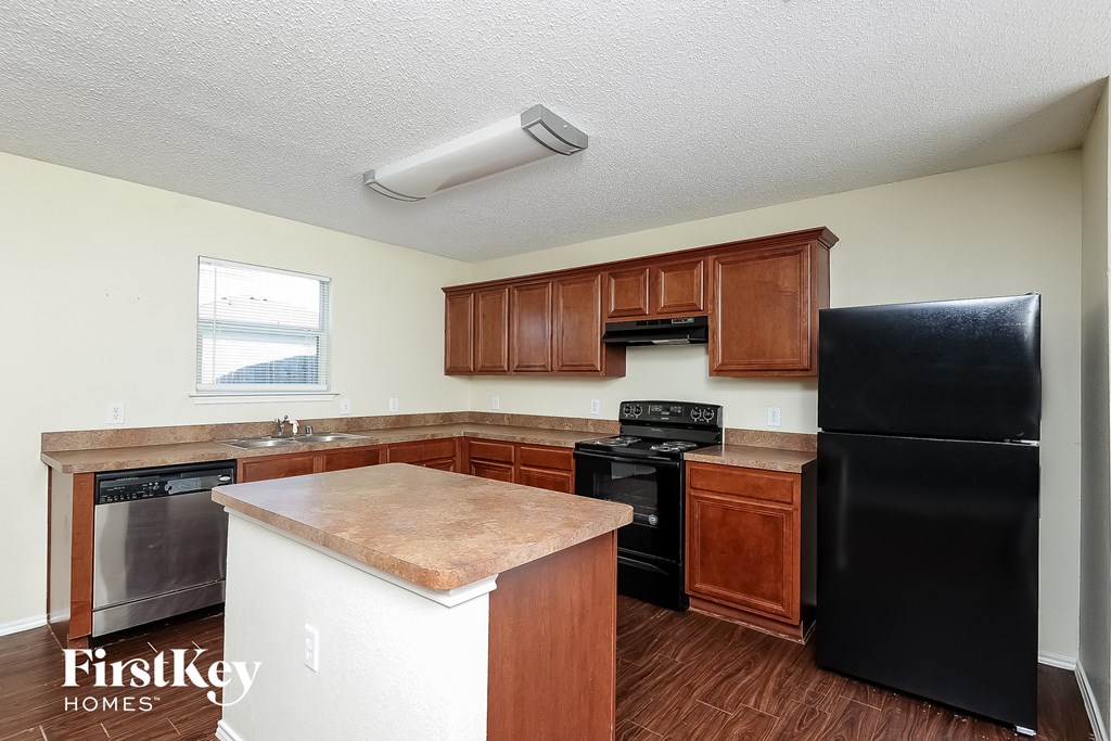 a kitchen with wooden cabinets and a black refrigerator