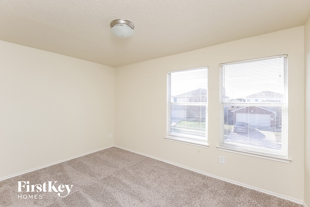 a bedroom with two windows and a carpeted floor