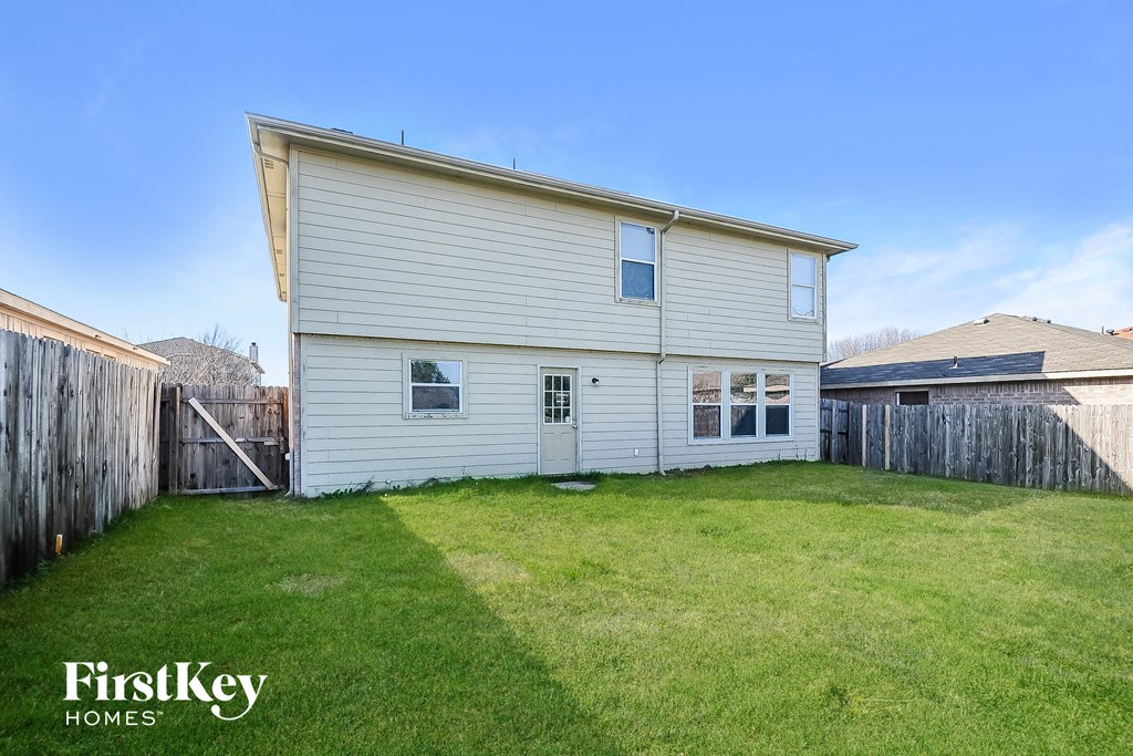 the back of a white house with a yard and a fence