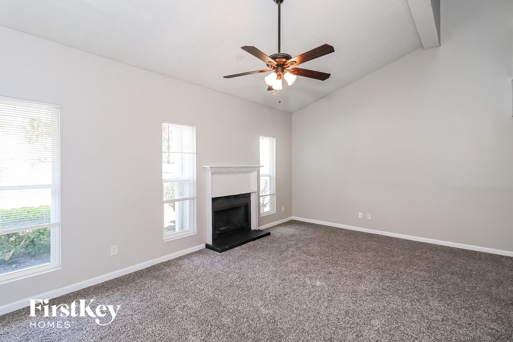 A spacious room with a fireplace and a ceiling fan.