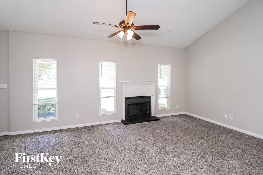A spacious living room with a fireplace and a ceiling fan.