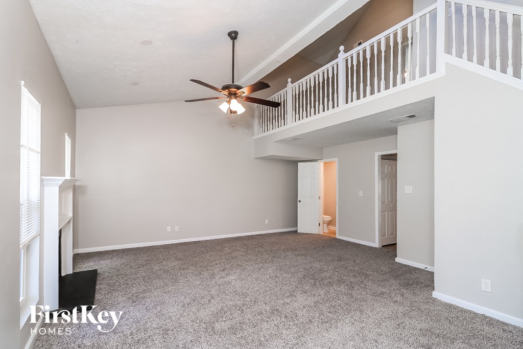 A spacious room with a ceiling fan and a balcony.