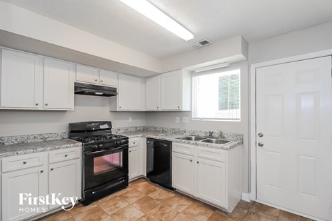 A kitchen with white cabinets and a black stove top oven.