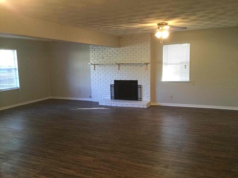 an empty living room with a fireplace and wood floors