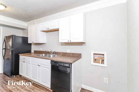 A kitchen with white cabinets and a black fridge.