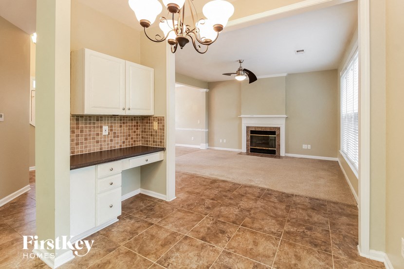 an empty living room with a kitchen and a fireplace