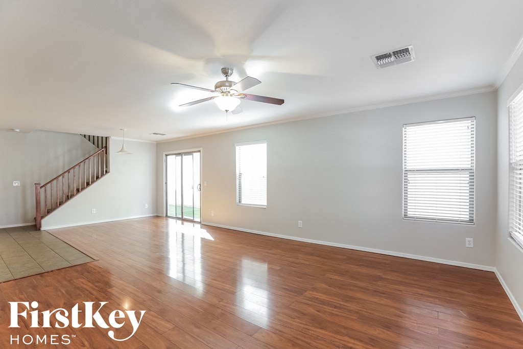 A spacious room with wooden floors and a ceiling fan.
