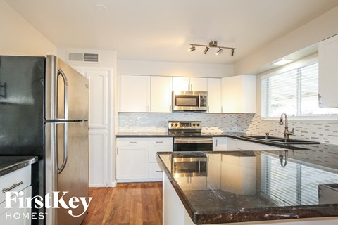 A kitchen with a black counter top and white cabinets.