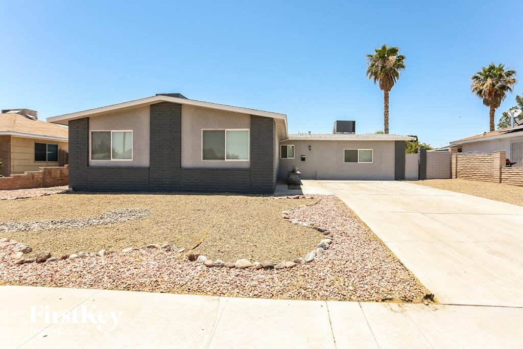 a small house with a driveway and palm trees