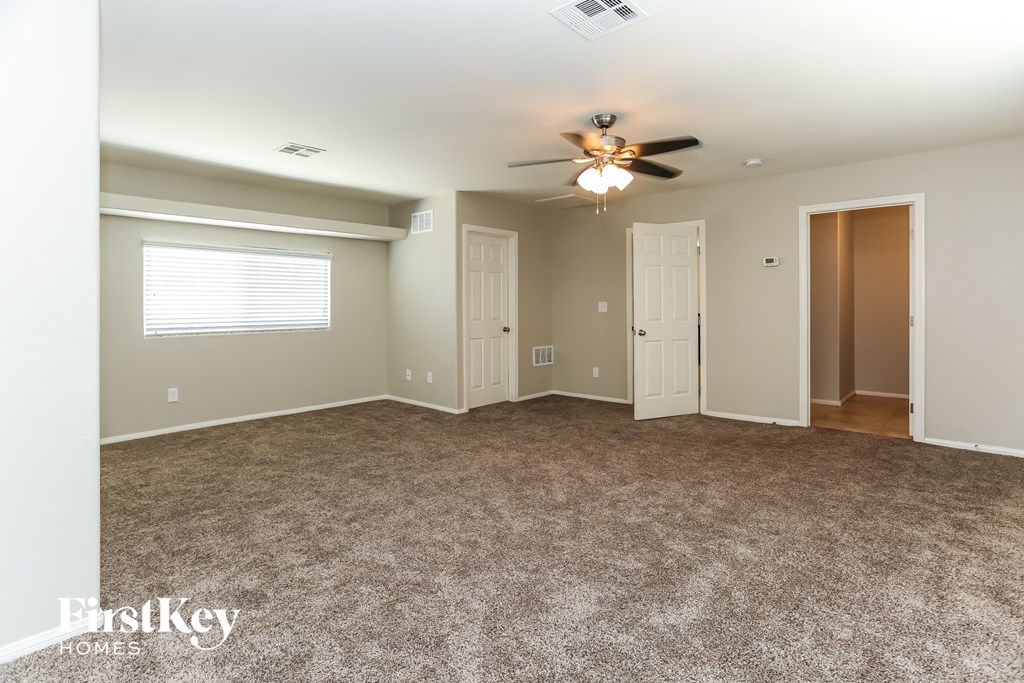 an empty living room with carpet and a ceiling fan