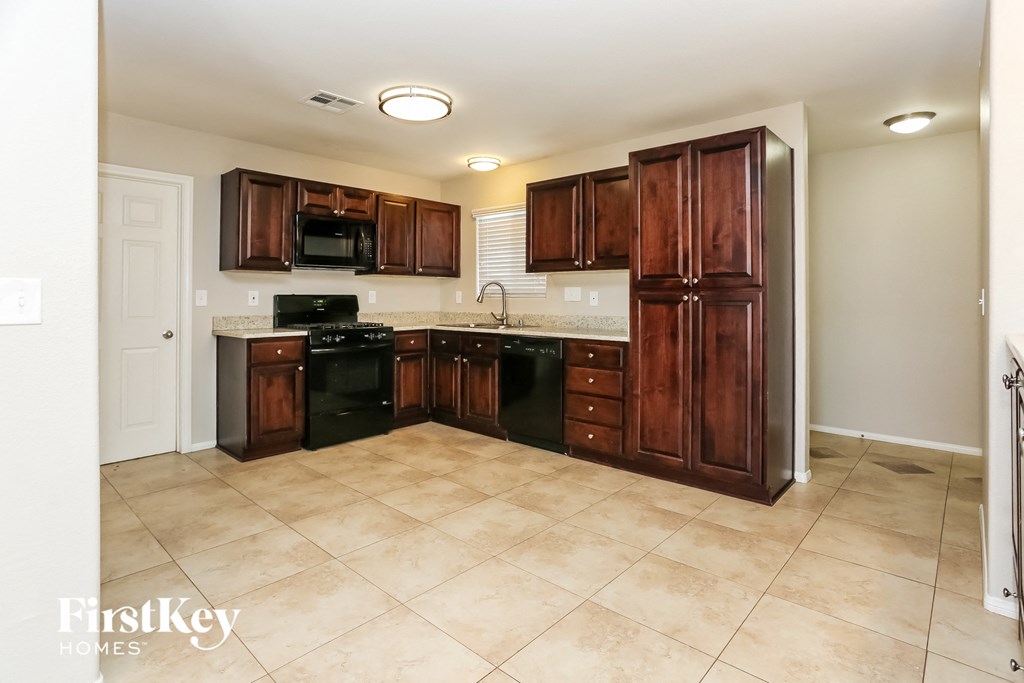 a kitchen with wooden cabinets and black appliances and tile floors