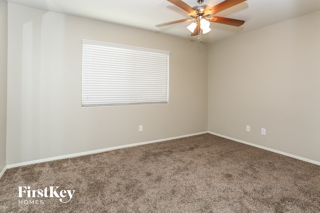 a carpeted room with a ceiling fan and a window