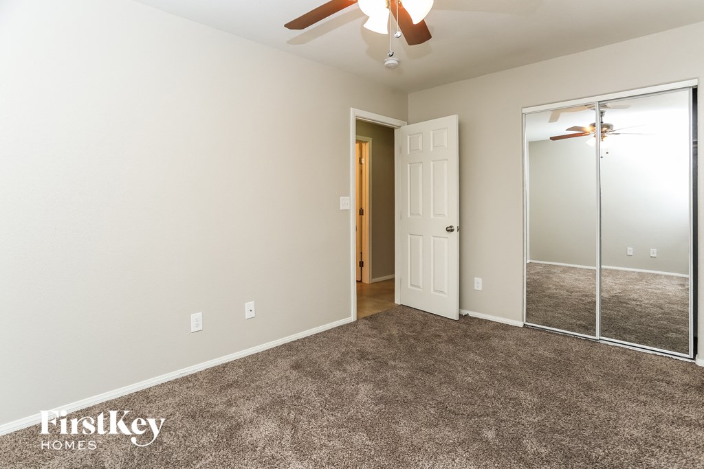 a bedroom with carpet and a ceiling fan and a mirrored closet