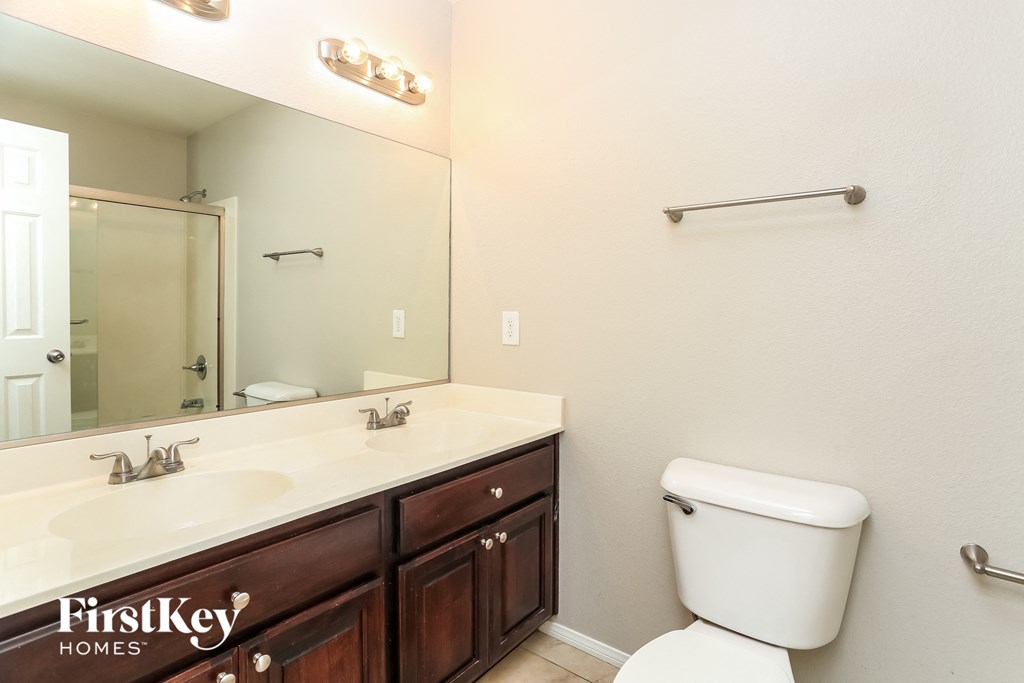 the master bathroom has a large vanity with two sinks and a toilet