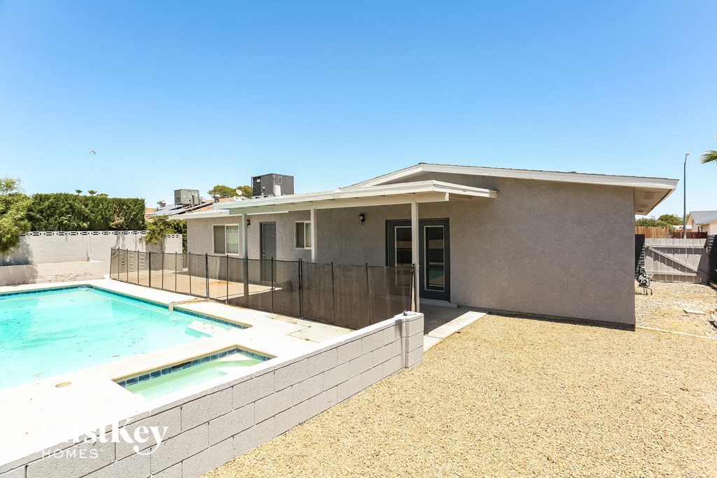 a house with a pool and a fence in front of it