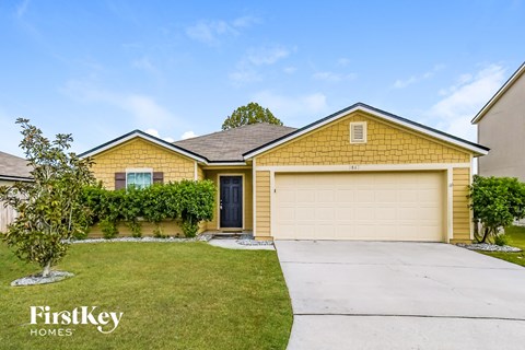 a yellow house with a driveway and a garage door