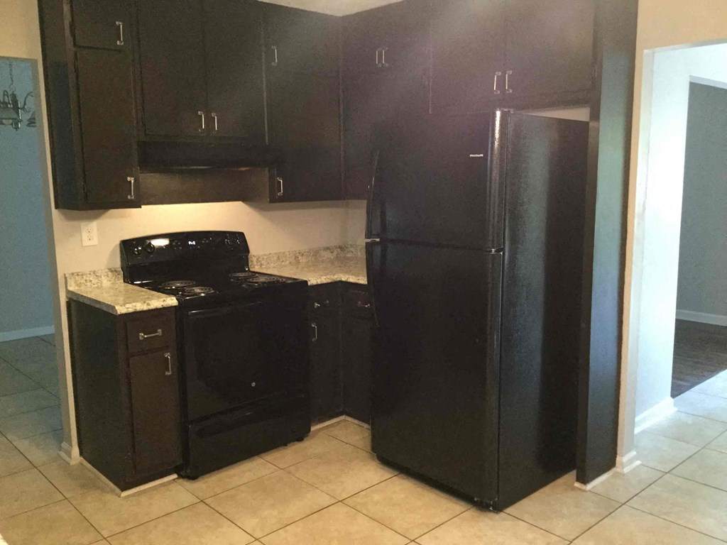 A black fridge and oven in a kitchen.