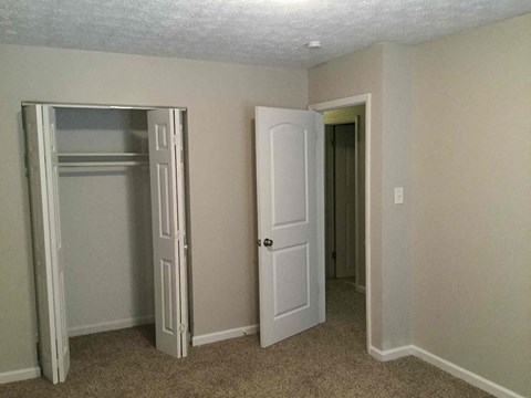A room with a white door and a white closet with a mirror.