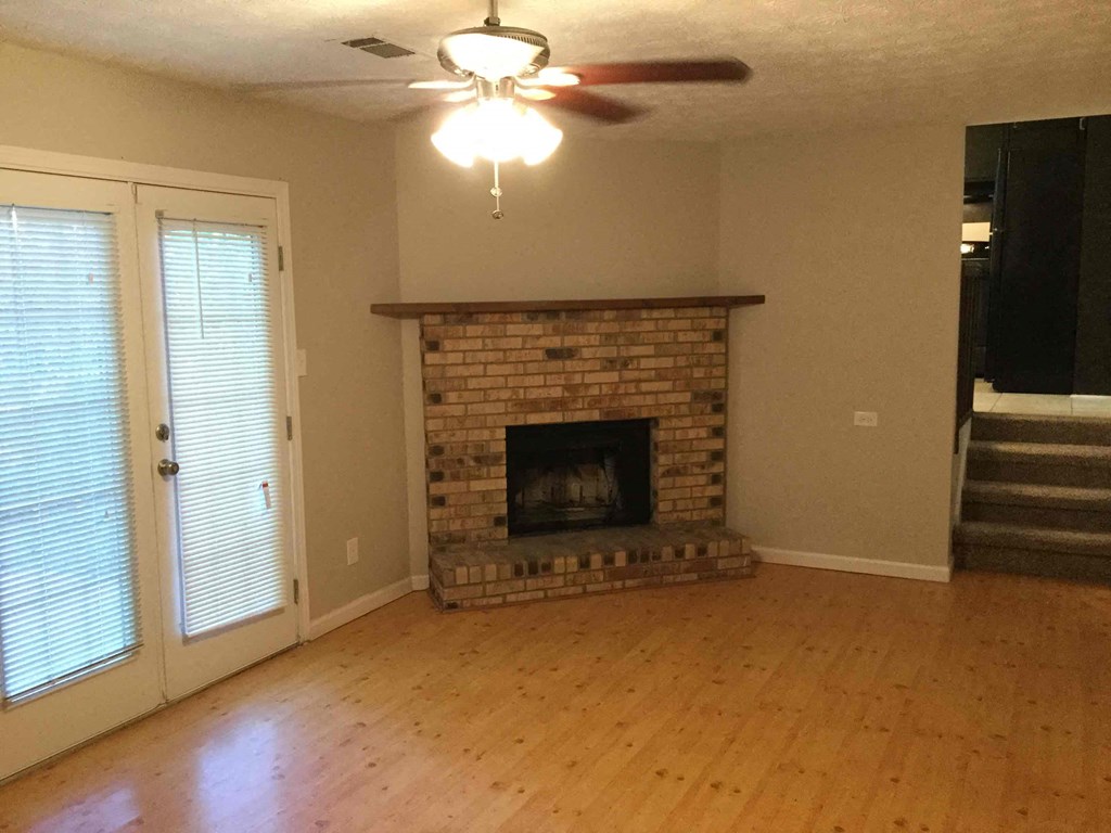A living room with a fireplace and a ceiling fan.