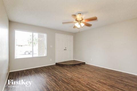 an empty living room with wood flooring and a ceiling fan