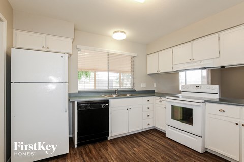 a kitchen with white cabinets and white appliances and a black dishwasher