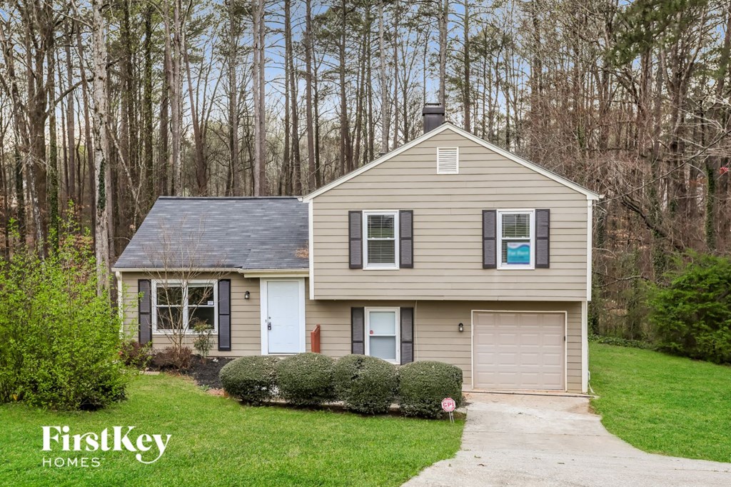 a small tan house with a yard and trees