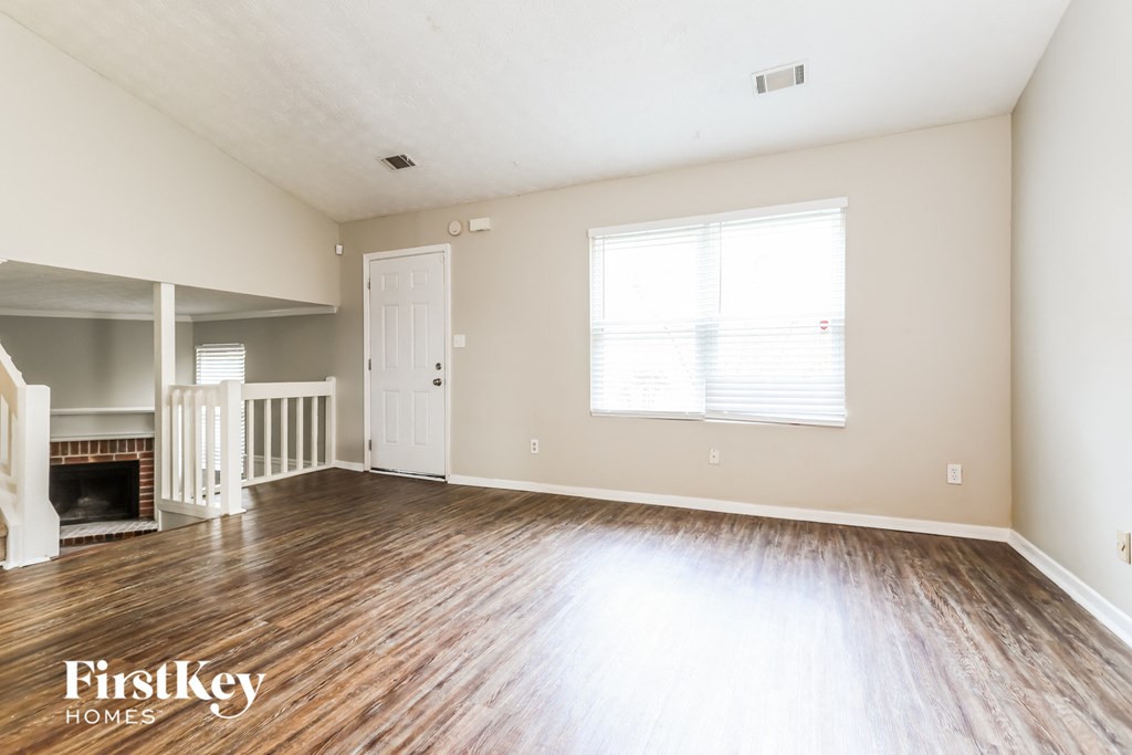 the living room of an empty house with wood floors and a fireplace