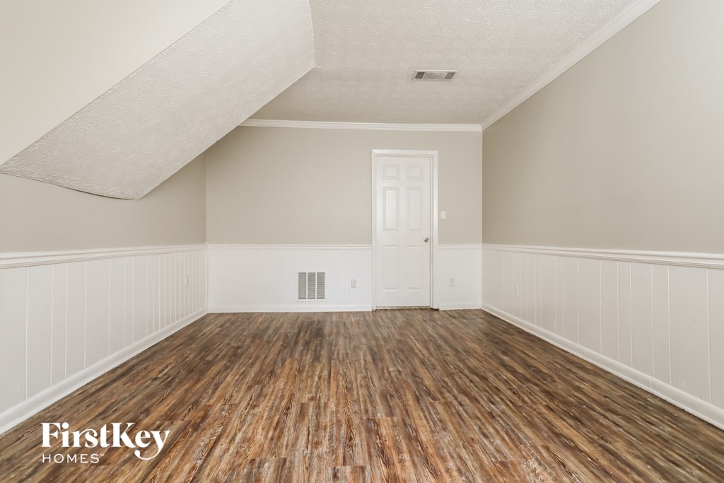 the living room of a home with wooden floors and a white door