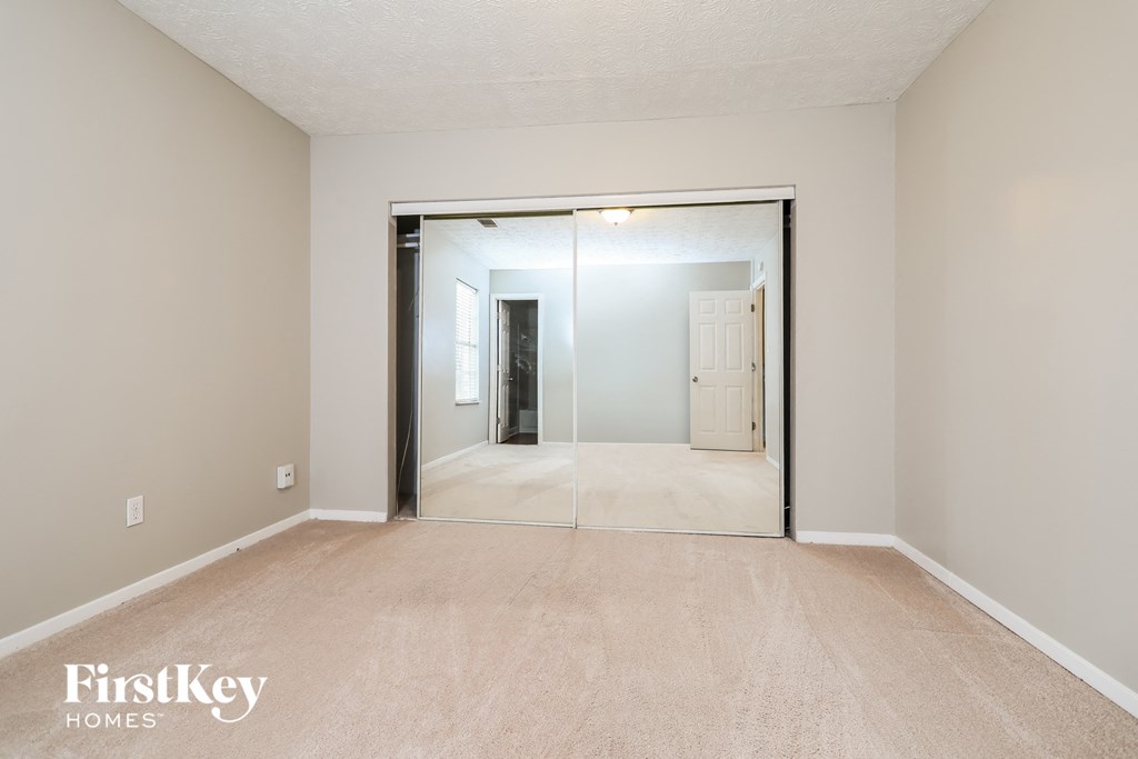 a spacious living room with a large mirror and carpeted flooring