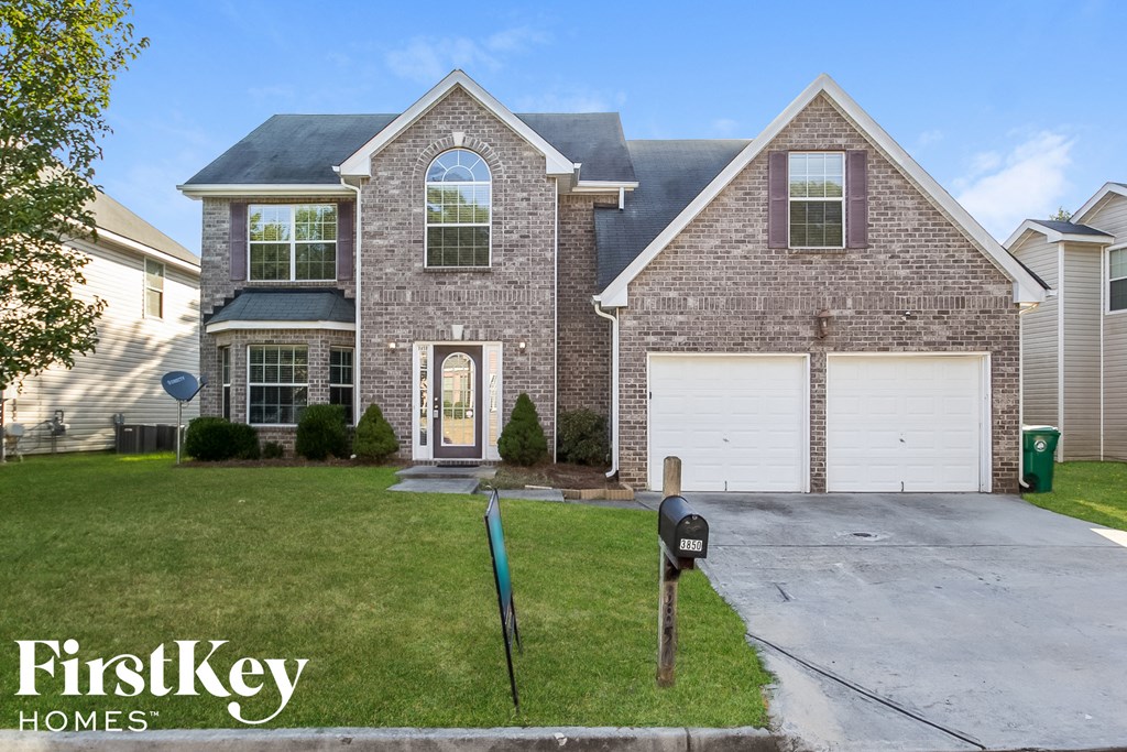 A brick house with a garage and a mailbox in front.