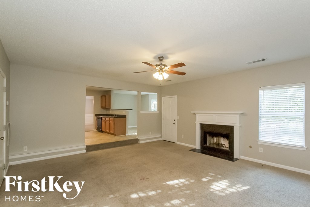 A spacious living room with a fireplace and a ceiling fan.
