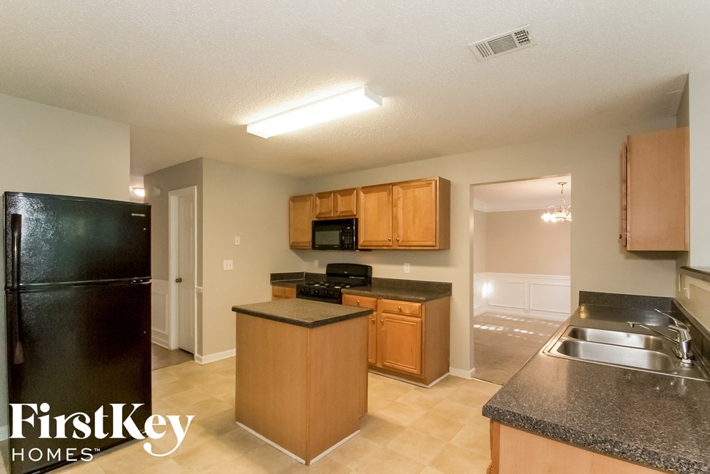 A kitchen with a black fridge and wooden cabinets.