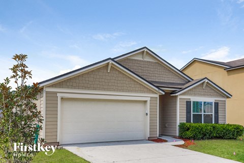 a beige house with a garage door and a lawn