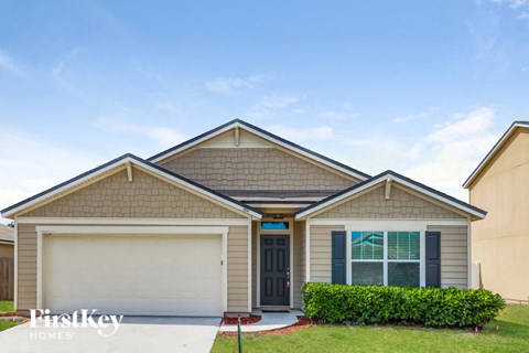 a beige house with a garage door and a lawn