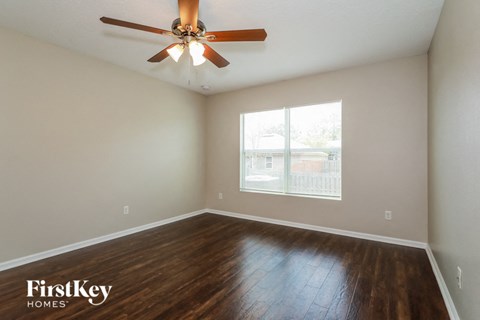 the spacious living room with hardwood flooring and a ceiling fan