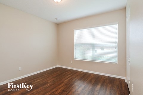the upstairs bedroom with hardwood flooring and a large window