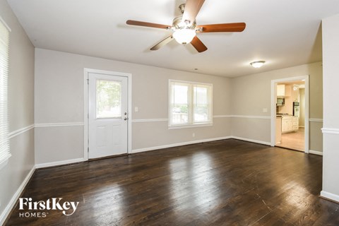 an empty living room with wood floors and a ceiling fan
