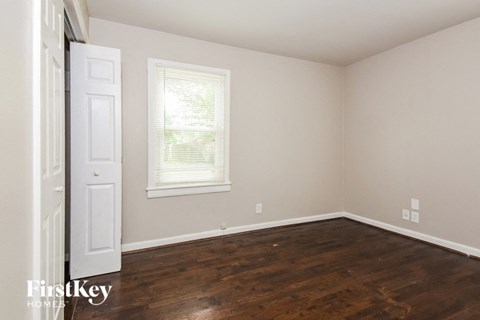 the bedroom of a home with wooden floors and a white door
