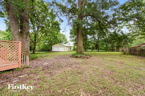 a yard with trees and a house in the background