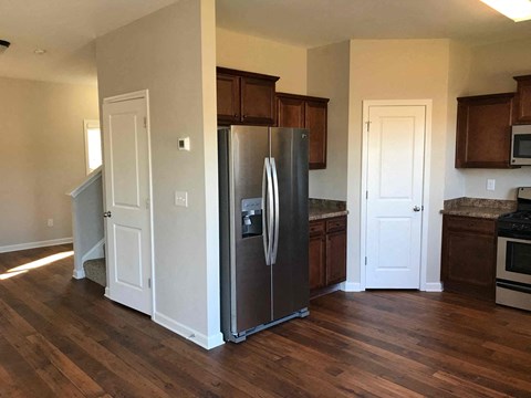 a kitchen with a stainless steel refrigerator and wooden floors