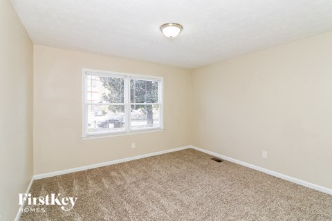 an empty bedroom with carpet and a window