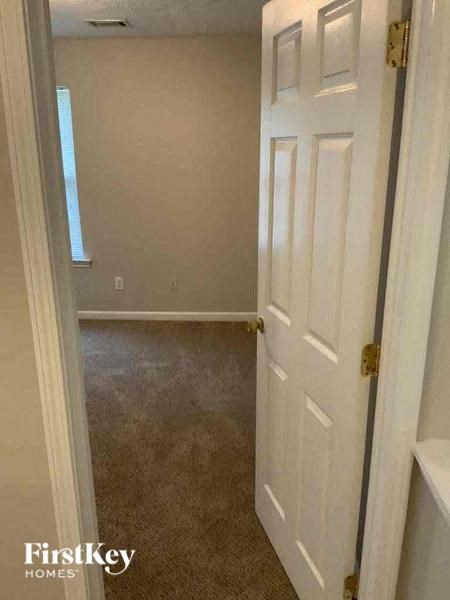 a hallway with a white door and a carpeted floor