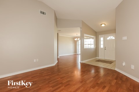 A spacious room with wooden floors and white walls.