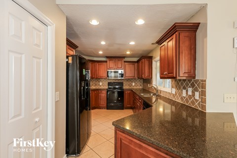 A kitchen with brown cabinets and a black refrigerator.