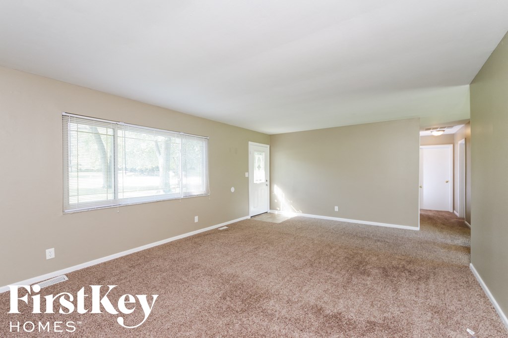 A spacious room with a carpeted floor and a window letting in natural light.