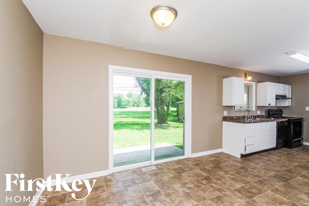 A kitchen with a tile floor and a sliding glass door leading to a green lawn.